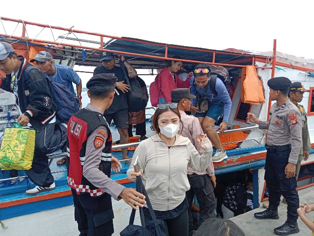 Polisi Baik Polsek Kepulauan Seribu Utara Bantu Penumpang Turun dari Kapal di Dermaga Pulau Harapan