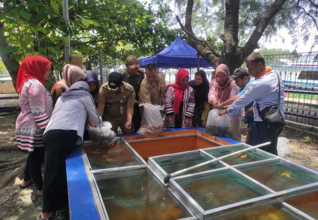 Bhabinkamtibmas Pulau Kelapa Dampingi Lurah Tabur Benih Ikan dalam Program Ketahanan Pangan  